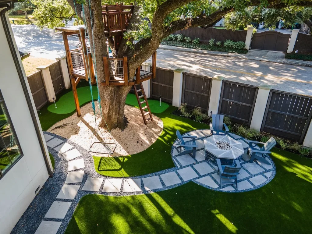 professional artificial turf installation with a tree house, playground, and a fire pit